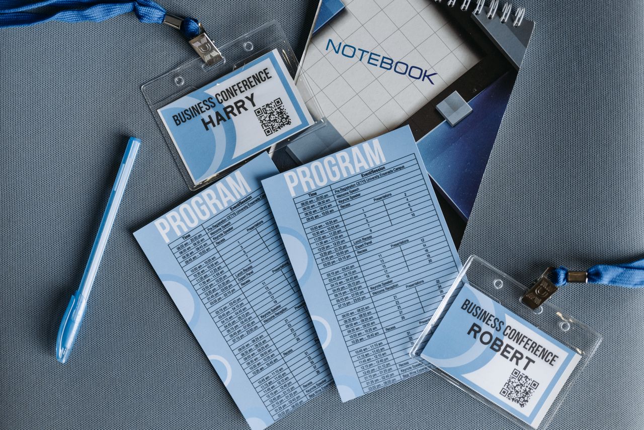 Home Flat lay of business conference materials including name tags, program, notebook, and pen.